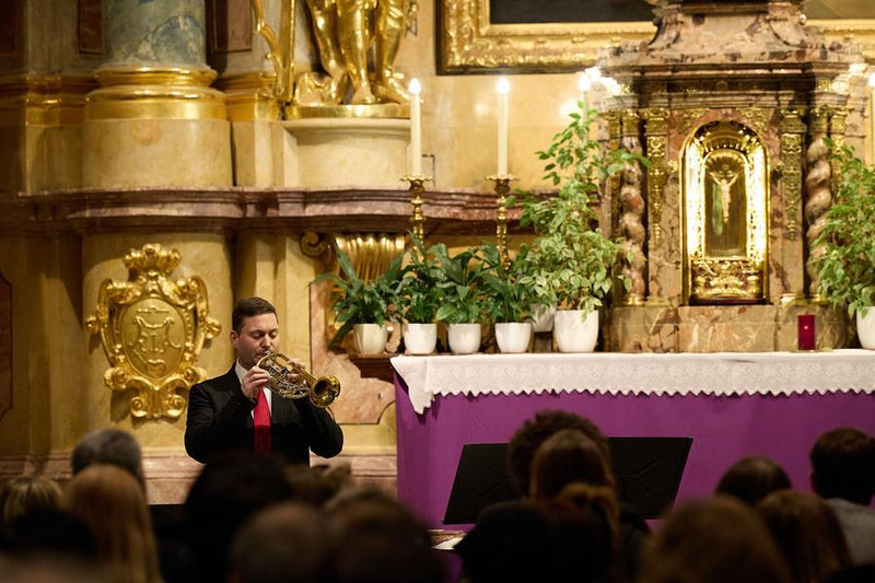 Trumpet and organ duo performing for an Advent audience in a baroque church setting.